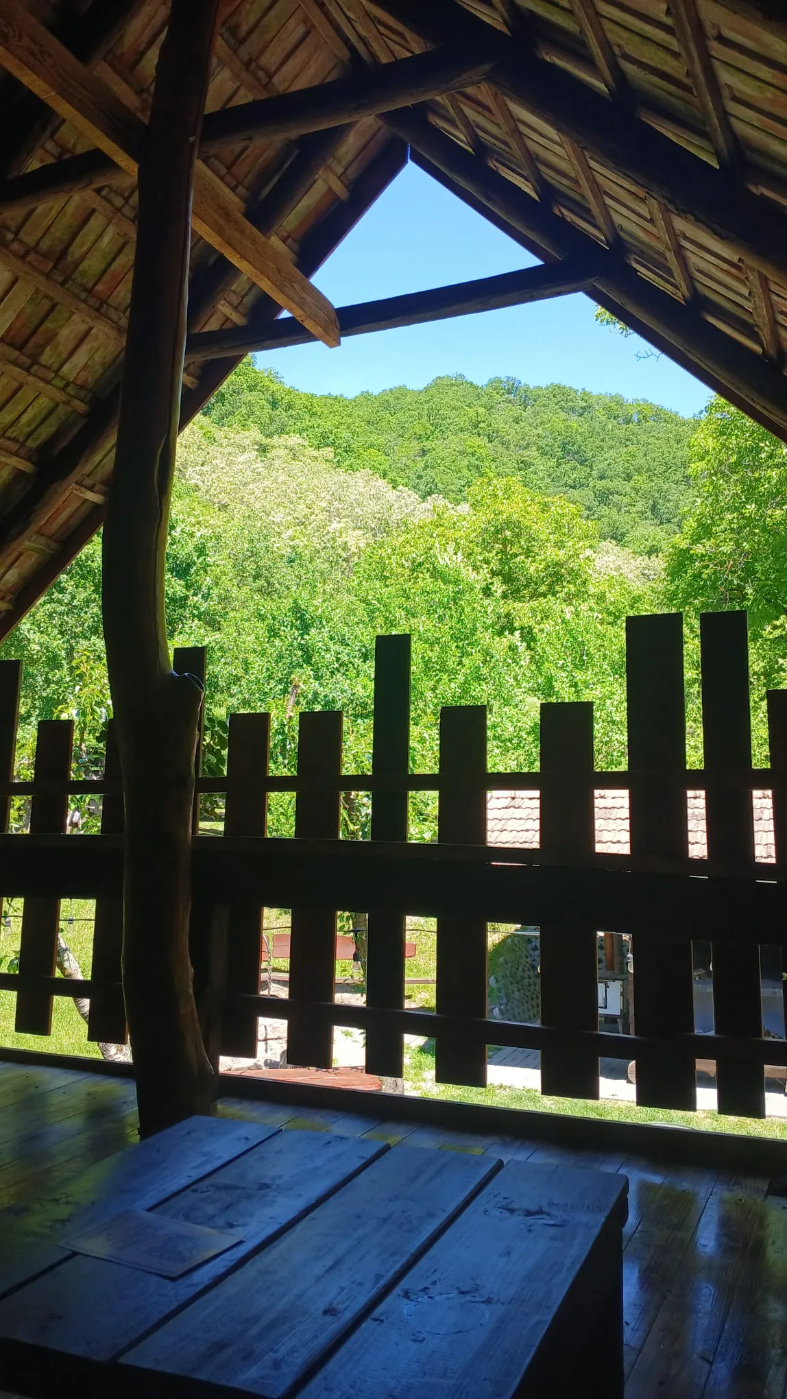 Covered wooden gazebo overlooking green hills