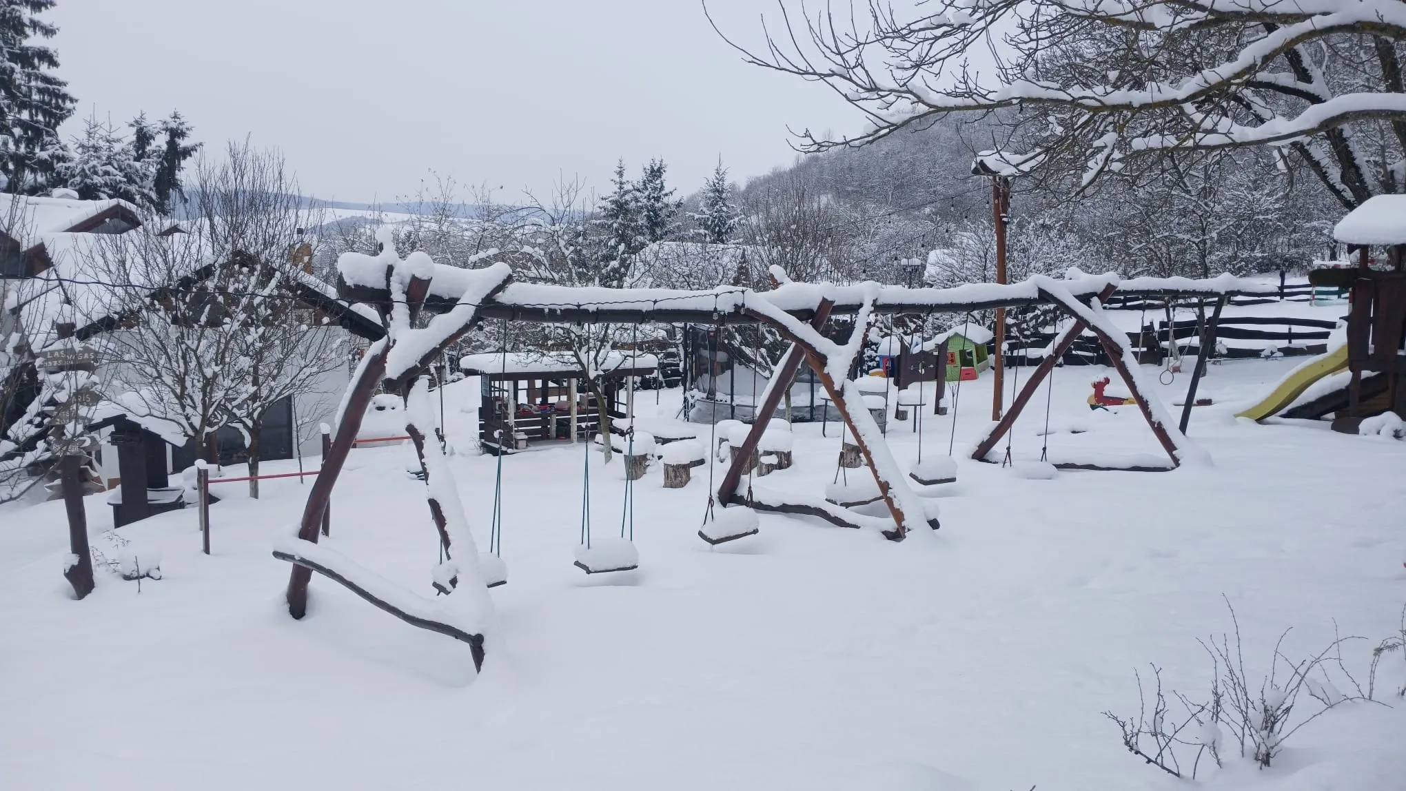 Snow-covered playground and yard in winter