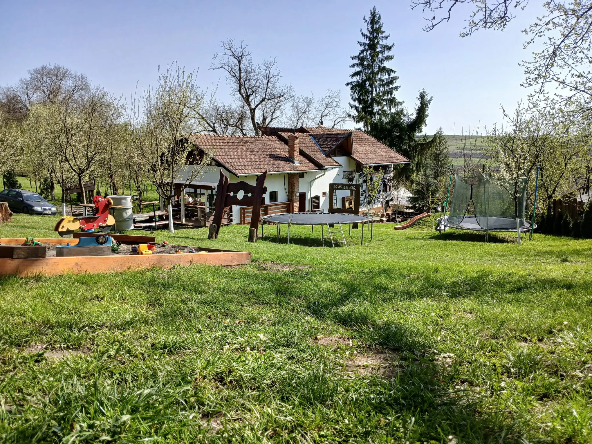 Yard with trampolines, a sandbox and the guesthouse