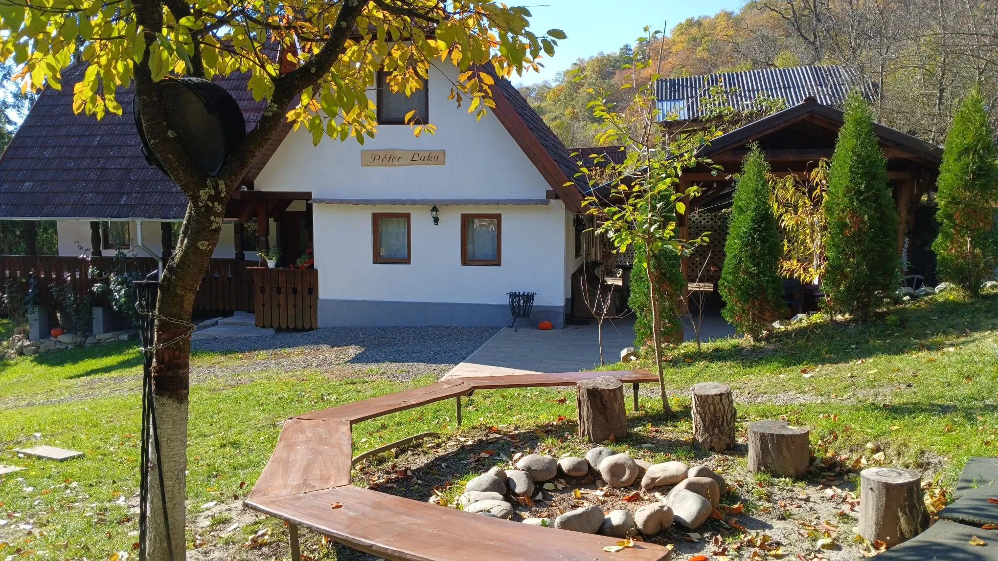 The Péter Laka cabin with its name board, seen across the garden in autumn