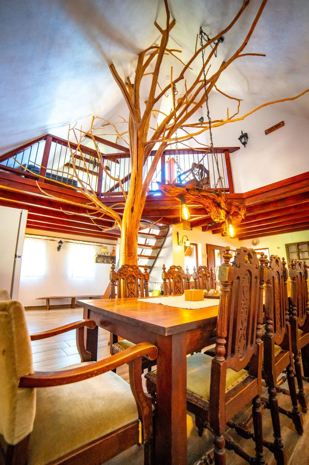 The old mulberry tree rising through the living room to the mezzanine, above the long carved dining table